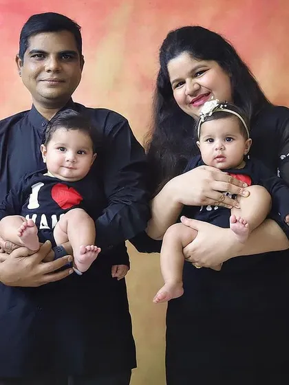 "Not double trouble, but twice blessed." This is a classic family portrait with parents proudly holding their twin babies, who are wearing adorable "I love Mama" shirts.