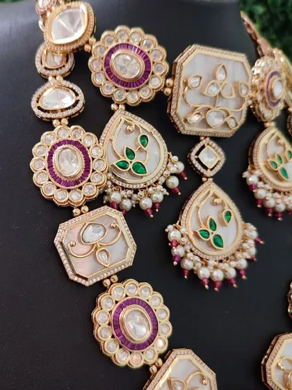 A close-up view revealing the delicate enamel painting and the sparkle of the surrounding stones. This set is a true work of art available for rent.