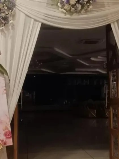 The entrance to a baby shower, decorated with white drapes and floral bouquets. A personalized welcome sign with a cute illustration adds a warm, personal touch.