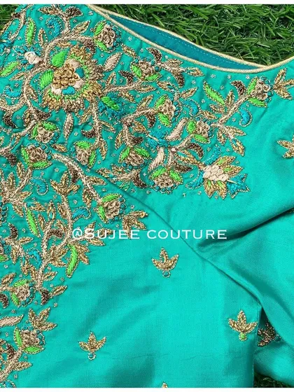 The neckline detail of the teal tree-of-life blouse. The intricate zardozi work creates a lush, garden-like effect on the rich silk fabric.