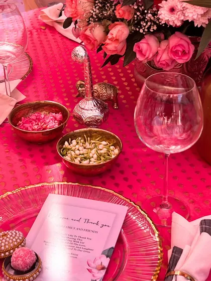 The table setting details, including a personalized welcome note for guests, bowls of fresh flower petals, and traditional silver accessories, all contributing to a thoughtful and welcoming experience.