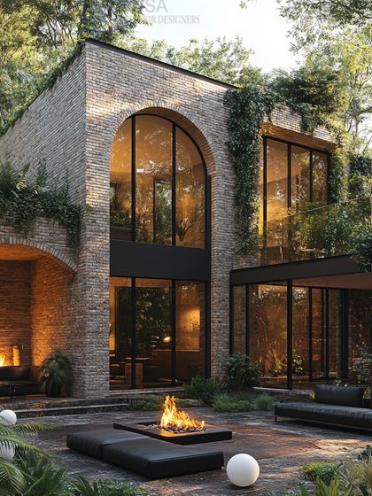 This design blends rustic brick arches with modern glass walls, creating a unique home that feels both grounded and open. The outdoor fireplace and fire pit extend the living space into the lush garden.