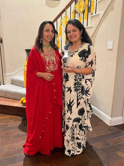 Here I am with a happy client. I'm wearing a red embroidered outfit with a statement necklace, and she looks lovely in a printed kaftan-style dress with elegant earrings.