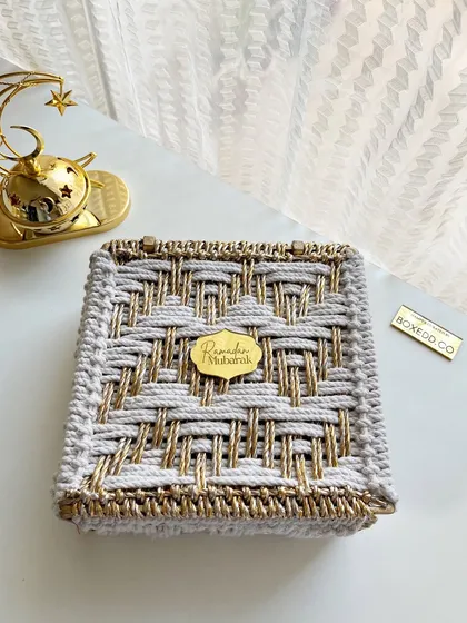 The exterior of the beautiful hand-woven Ramadan gift box, featuring a gold and silver thread design and a "Ramadan Mubarak" tag.