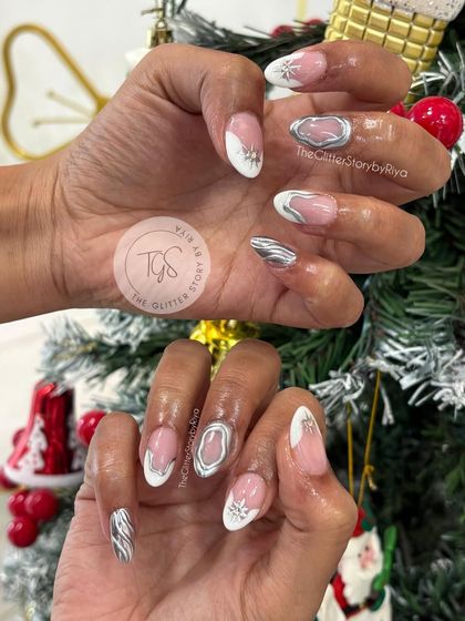 A festive winter nail set with 3D elements. This design combines a white French tip with sculpted silver swirls and a textured snowflake accent nail.