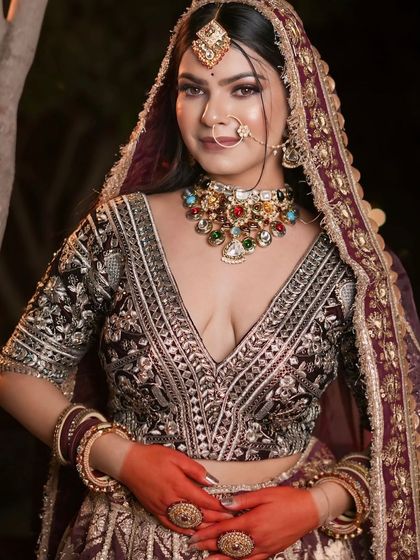 A series of portraits of a bride in a deep wine-colored lehenga. The outdoor, nighttime setting shows the outfit's versatility for reception or sangeet shoots.