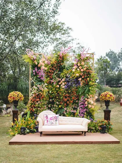 A beautiful photo booth for the English garden wedding, featuring a vintage chaise lounge set against a lush wall of colorful, wild-looking flowers.