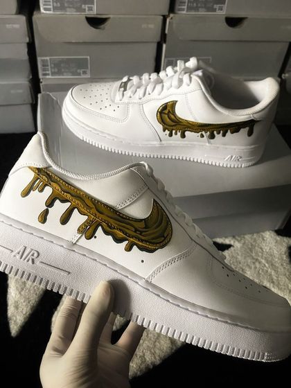 The liquid gold drip custom sneaker held up for a detailed view.