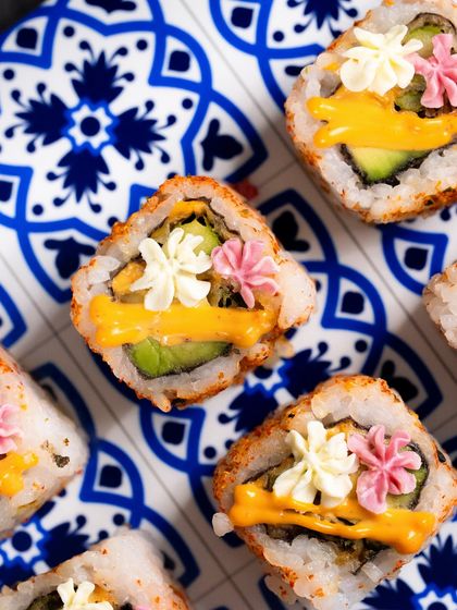 A top-down view of the Avocado Asparagus Tempura rolls, decorated with edible flowers.