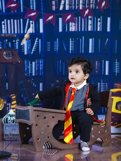 Our little wizard is ready to cast a spell with his wand, sitting at his desk with a look of concentration.