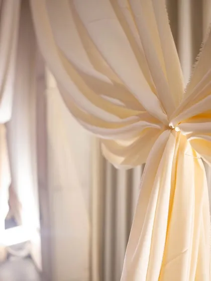 The beauty of fabric. Elegant ivory drapes are tied back to create soft, flowing lines, adding texture and warmth to the event space.