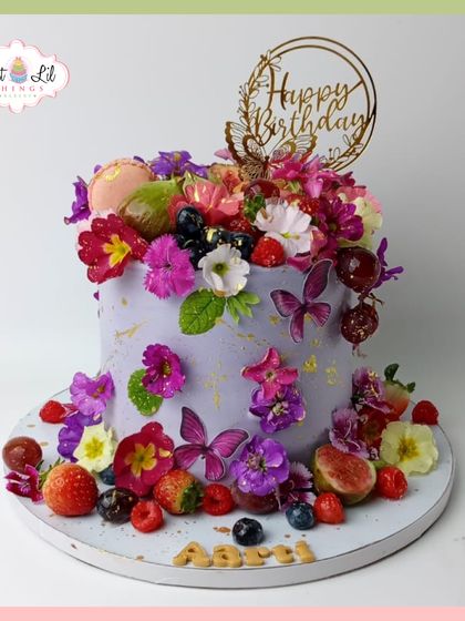 A garden in full bloom on a cake. This lavender-colored cake is overflowing with fresh flowers, berries, and delicate butterfly details.