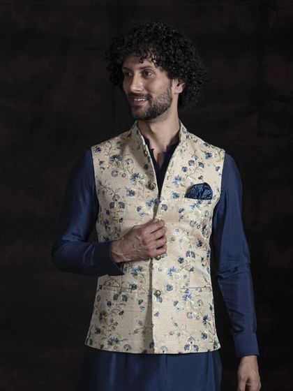 This floral printed Nehru jacket in beige and blue offers a fresh and modern take on traditional layering. Paired with a deep blue kurta, it creates a look that is both stylish and appropriate for semi-formal gatherings.