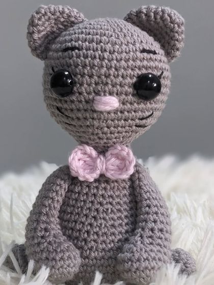 A dapper grey cat amigurumi wearing a little pink bowtie.