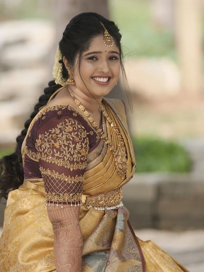 A radiant welcome look for the bride Tejeshwini. Her golden silk saree is complemented by warm, glowing makeup and a beautifully detailed traditional hairstyle.