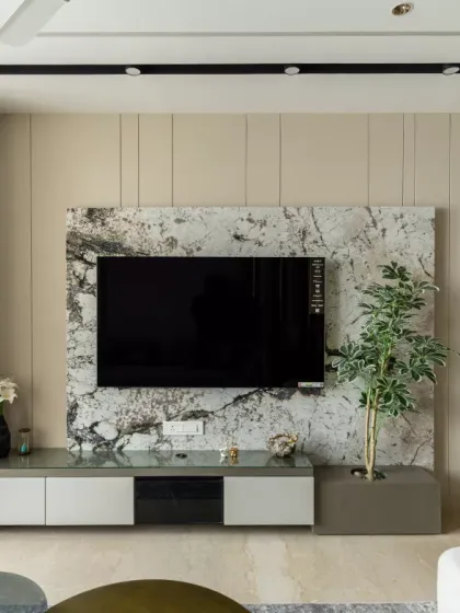 A harmonious blend of luxury and functionality, this TV unit design is a statement of timeless elegance. The exquisite marble backdrop adds depth and opulence, seamlessly complementing the neutral-toned paneling and a subtly integrated mandir shutter.
