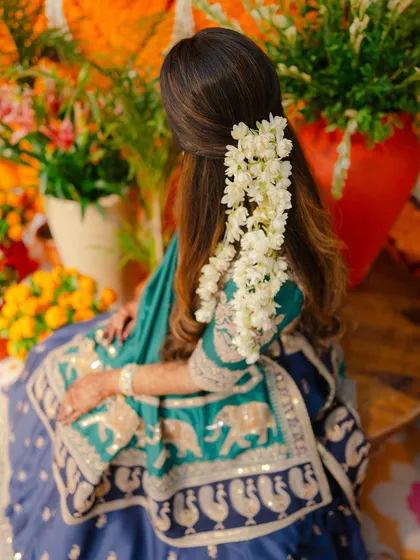 A beautiful view of a half-up hairstyle decorated with a cascade of fresh white flowers. This style is both elegant and relaxed, ideal for a daytime pre-wedding event.