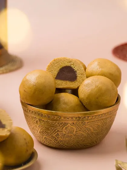 Besan Laddoos with a chocolate filling. The bokeh from the festive lights in the background adds a magical touch to this Diwali-themed shot.