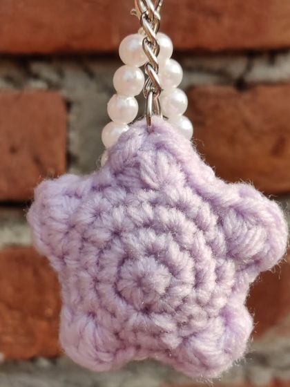 Puffy star-shaped keychains, available in pastel colors like lavender and peach, with an optional pearl strap.