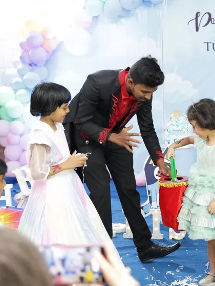 I make sure the kids are the stars of the show. Here, I'm getting some help from two young audience members for a classic "magic bag" illusion at a 5th birthday party. It's all about participation and laughter.