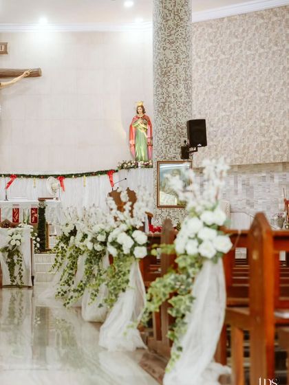 A side view of the aisle, showing the beautiful floral arrangements that guide the way to the altar. The combination of white flowers and green ivy is a timeless choice for church decor.