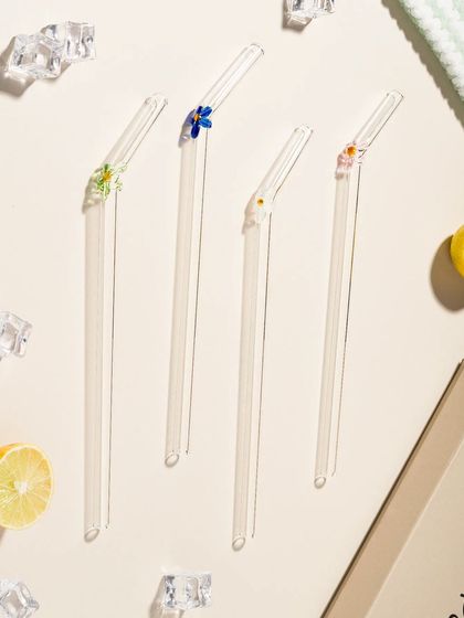 A flat lay of beautiful glass straws with floral details. This top-down, artistic arrangement is perfect for social media and lifestyle blogs.