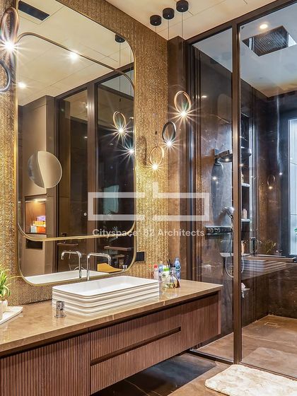 We transformed this bathroom into a luxurious retreat. A sleek, textured sink and a rounded mirror with metallic accents create a striking focal point, enhanced by a refined blend of wood, stone, and metal.