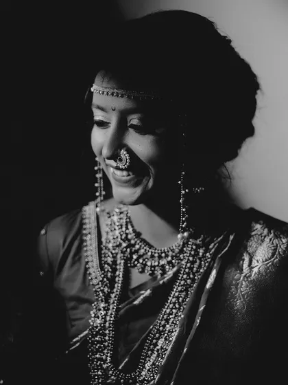 Black and white photography strips away distractions and reveals pure emotion. This artistic bridal portrait uses a high-contrast, film-noir style to highlight the bride's joyful expression and the intricate details of her traditional Maharashtrian jewelry.