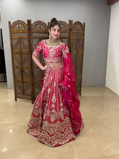 Another angle of the vibrant rani pink bridal lehenga. The full skirt is adorned with intricate patterns, making it a breathtaking choice for your wedding ceremony.