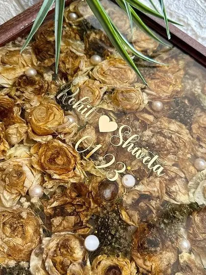 Crafted with love, sealed with resin. This square teakwood frame holds a couple's varmala, with their names and wedding date floating above the preserved flowers. It's a beautiful way to keep wedding memories alive.