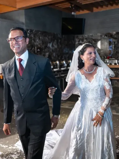 The happy couple makes their entrance into the reception hall, smiling as they walk through a shower of petals. A classic, candid moment.
