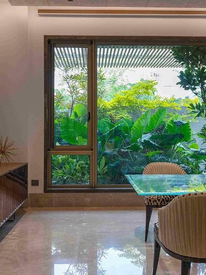 A dining area with a large window that perfectly frames a view of the lush garden outside. This intentional framing turns the landscape into a piece of living art for the homeowners to enjoy.