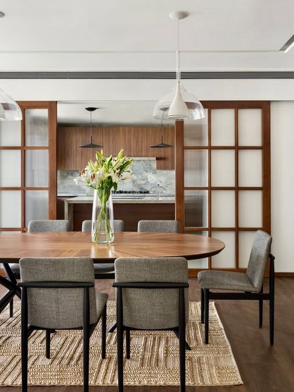 Sliding doors with fluted glass offer a glimpse from the dining room into the kitchen of the West Coast Residence, providing a sense of connection while keeping the spaces distinct.
