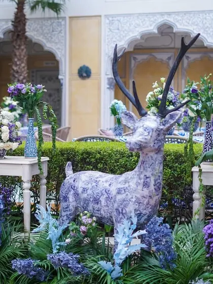 A closer view of the patterned deer statue, showcasing the detail of the design and the lush floral arrangement at its base. It stands as a unique piece of art within the decor.