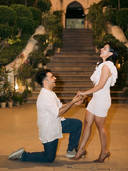 The classic proposal moment, with the groom on one knee, and the bride's reaction of pure joy and surprise.