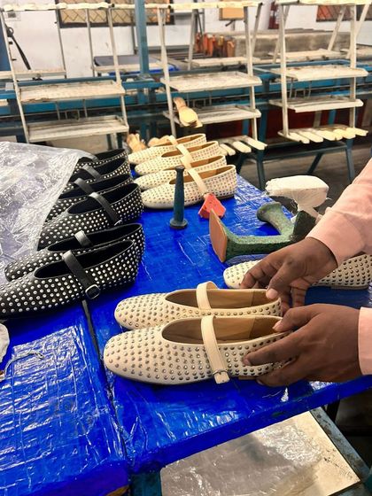 A behind-the-scenes look at the final inspection of our Ecru and Black Rivet Ballet Flats. An artisan carefully checks each pair, ensuring the quality and craftsmanship meet my exacting standards before they reach you.