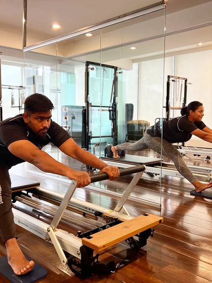 A group of clients performs a hamstring stretch on the Reformer. This is a great way to improve flexibility and release tension in the back of the legs.