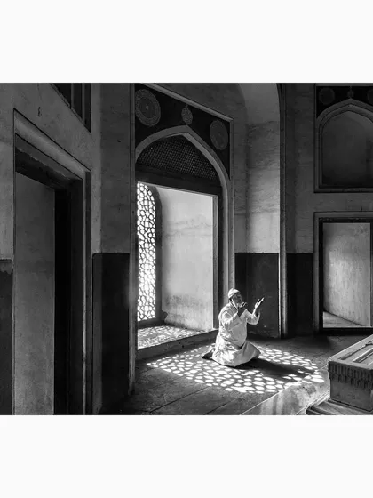 A moment of quiet prayer inside a tomb, where light filters through a jali window, creating a pattern on the floor. This image is about the interplay between light, shadow, and faith. It is a contemplative piece of documentary art that speaks to a universal sense of spirituality.