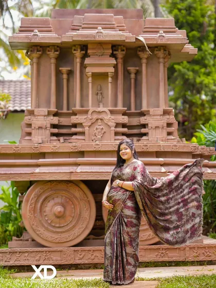 A flowing saree shot, capturing movement and grace as the mother-to-be stands before the stone chariot.
