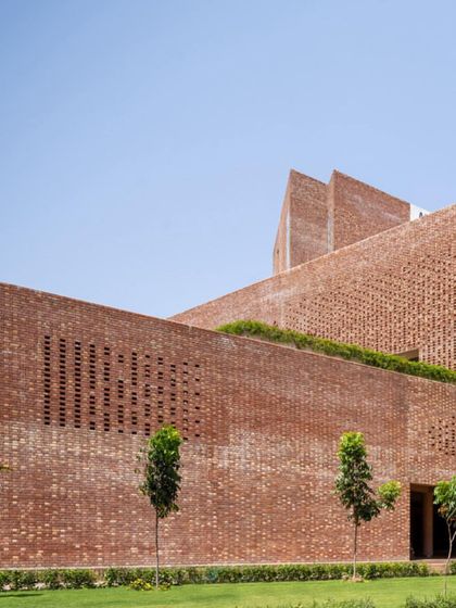 The building's facade features perforated brick screens, or jalis, that create a textural surface and help to naturally ventilate the interiors.