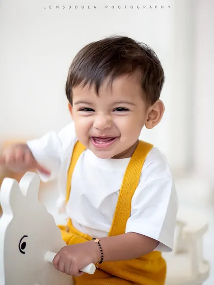 A giggle that's pure gold. This happy boy is having the time of his life on the rocking horse in our simple and classic studio setup.