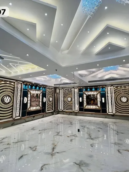 A wide shot of the empty Grand Utsav Banquet hall, showcasing the beautiful marble floor and the detailed, modern wall decor.