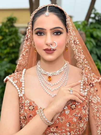 A direct, confident look from the bride. Her makeup is powerful yet elegant, with perfectly defined brows and a bold lip that commands attention.