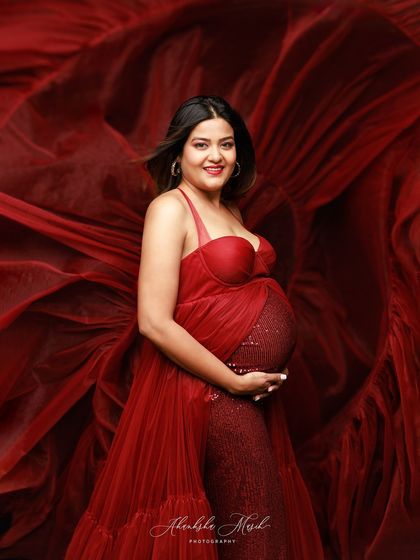 A full-body shot of the stunning red sequin and tulle gown, with the fabric creating a dramatic, flowing backdrop.