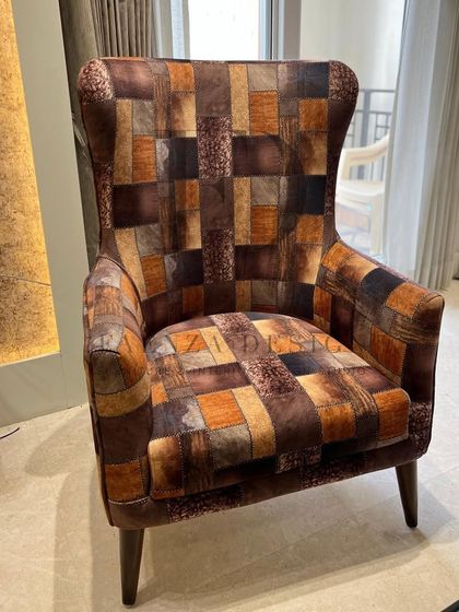 A high-back armchair upholstered in a unique, multi-toned patchwork fabric. This chair is a piece of art, adding texture, color, and a one-of-a-kind personality to the room.