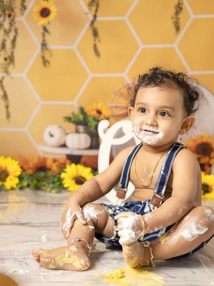 The aftermath of a successful cake smash. This little one is covered in frosting from head to toe, a perfect memory of a fun-filled first birthday celebration.