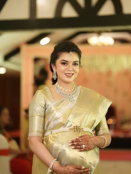 A beautiful portrait of Monica cradling her baby bump. Her makeup is soft, elegant, and perfectly enhances her natural pregnancy glow for her baby shower celebration.