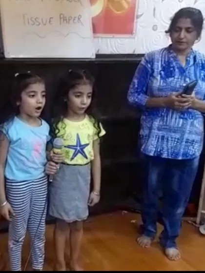Two young girls sing a duet into the microphone, learning to harmonize and perform together during our vocal training workshop.