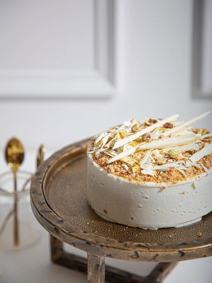 Our Vanilla Raspberry ice cream cake, topped with white chocolate shards and toasted pistachios. The alternating layers of vanilla sponge and raspberry sorbet create a refreshing delight.