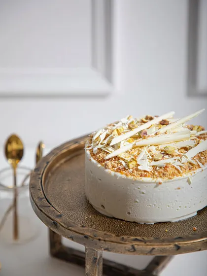 Our Vanilla Raspberry ice cream cake, topped with white chocolate shards and toasted pistachios. The alternating layers of vanilla sponge and raspberry sorbet create a refreshing delight.